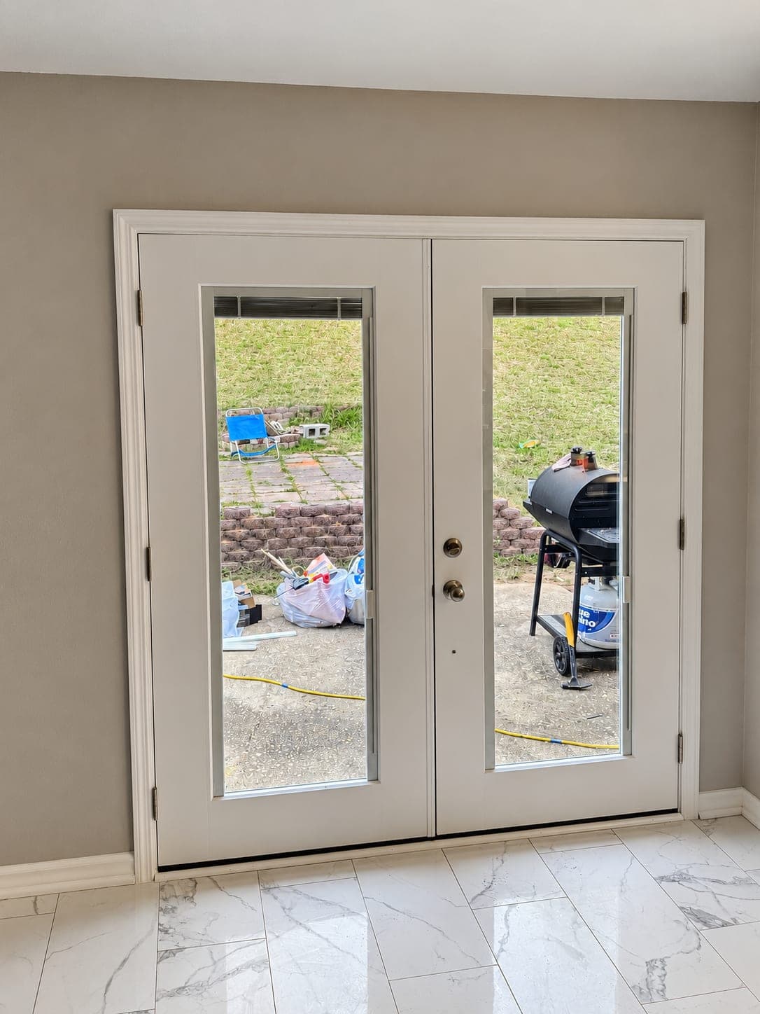 New white French doors with built-in blinds seen from inside the house