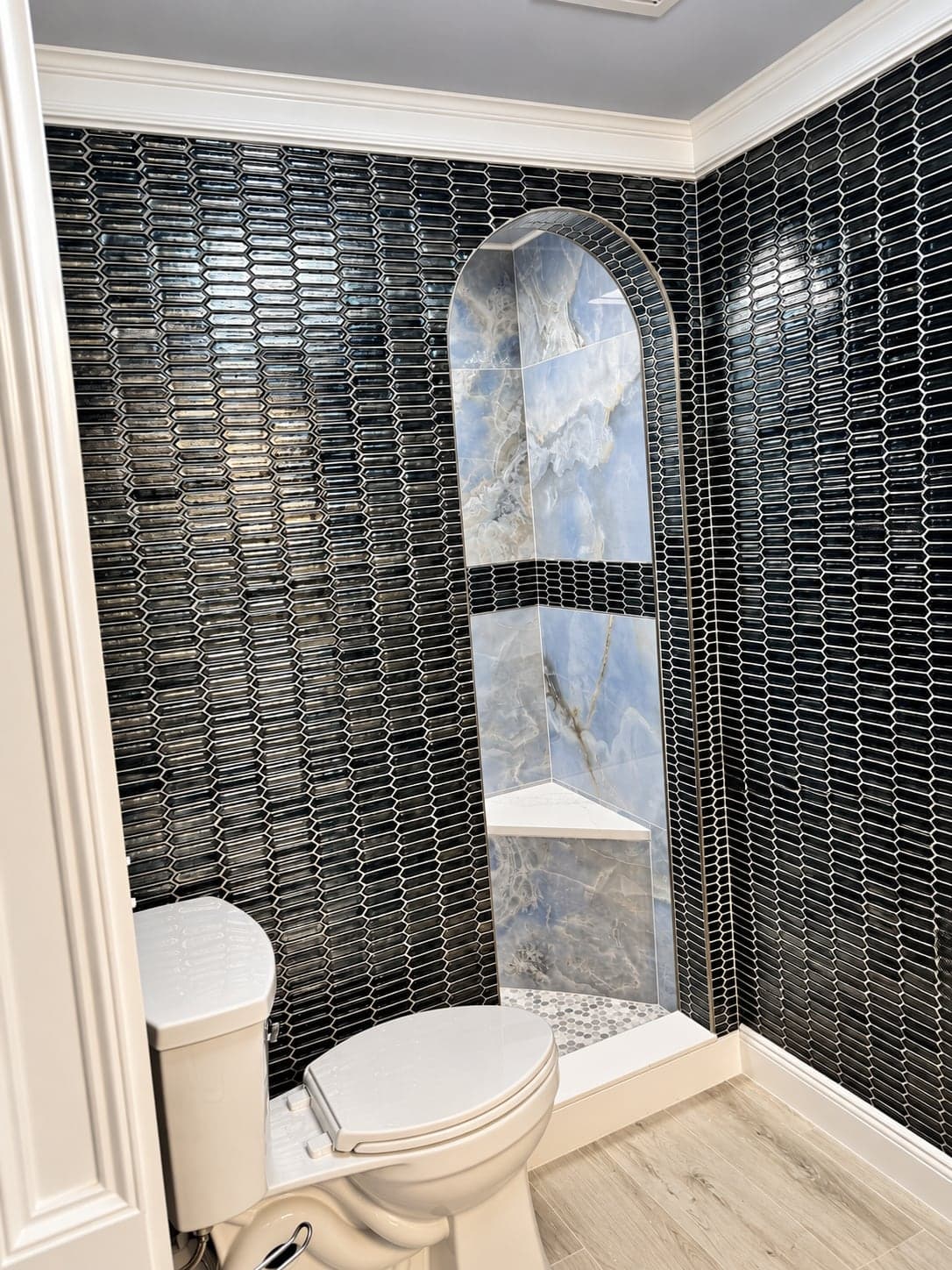 Arched shower opening finished in dark blue tile with blue onyx walls