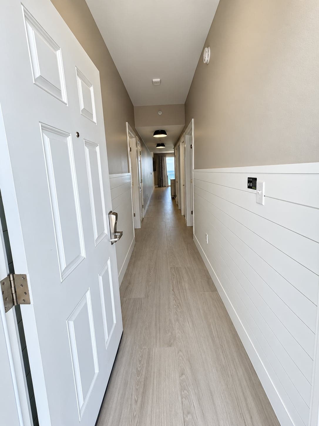 Gulf-front condo hallway with white shiplap wainscoting and a new floor