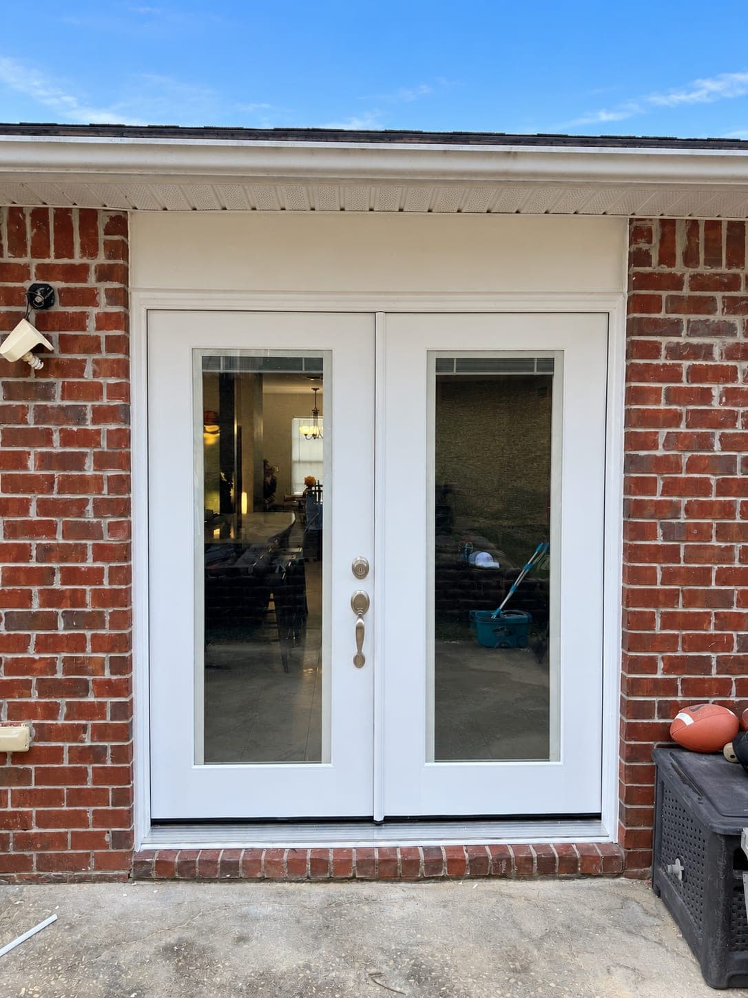 New white French doors with built-in blinds on the back of a brick house