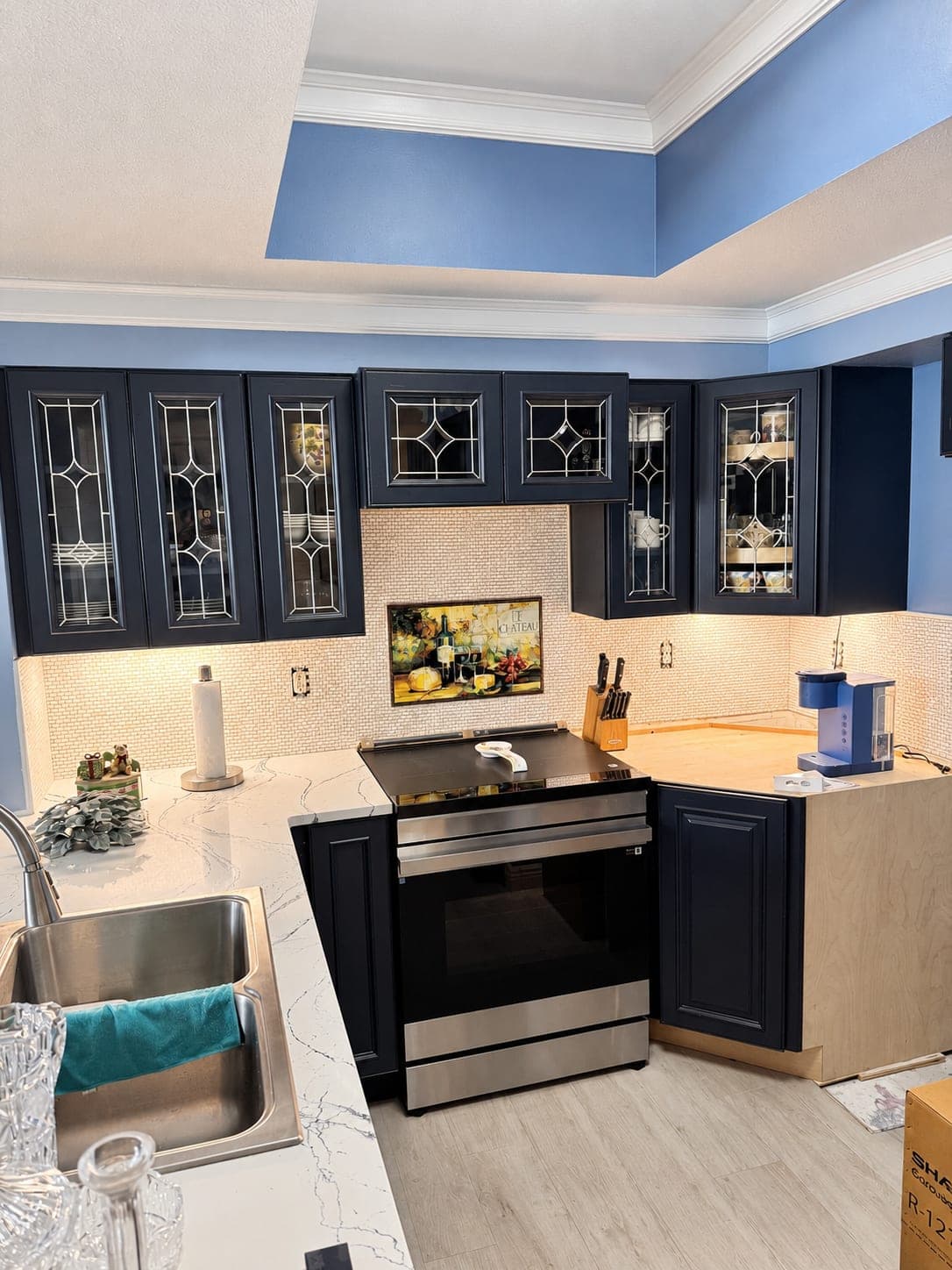 Kitchen with navy cabinets, glass-front uppers, white tile backsplash and a stainless range