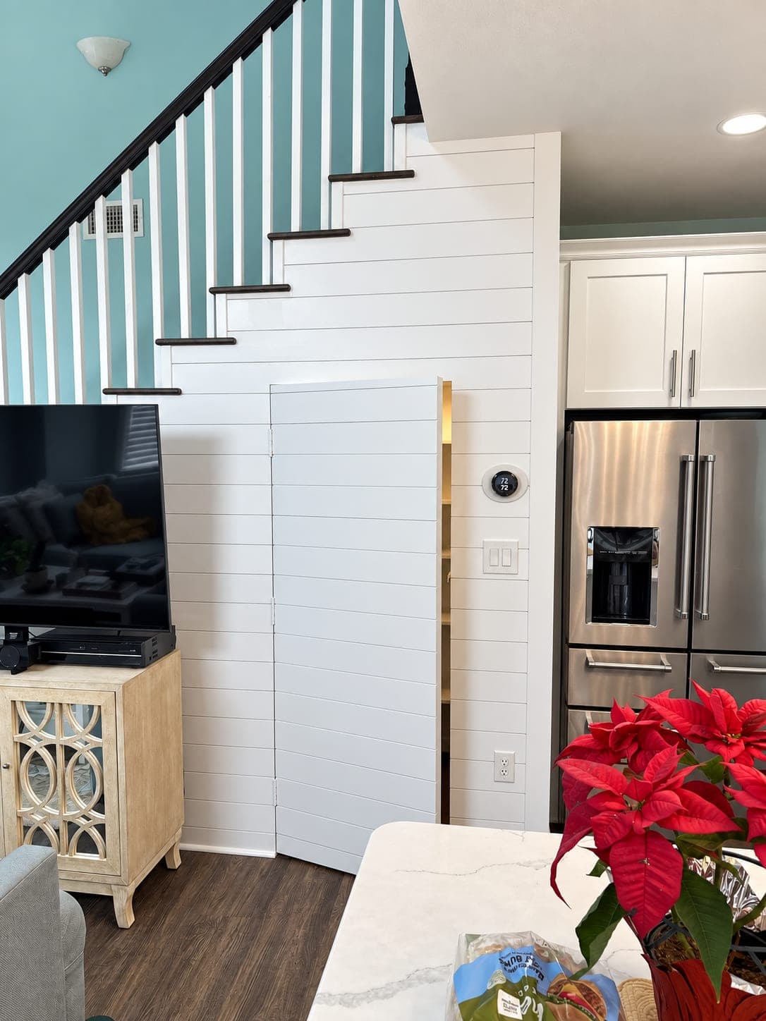 Built-in pantry under a shiplap staircase, beside the refrigerator