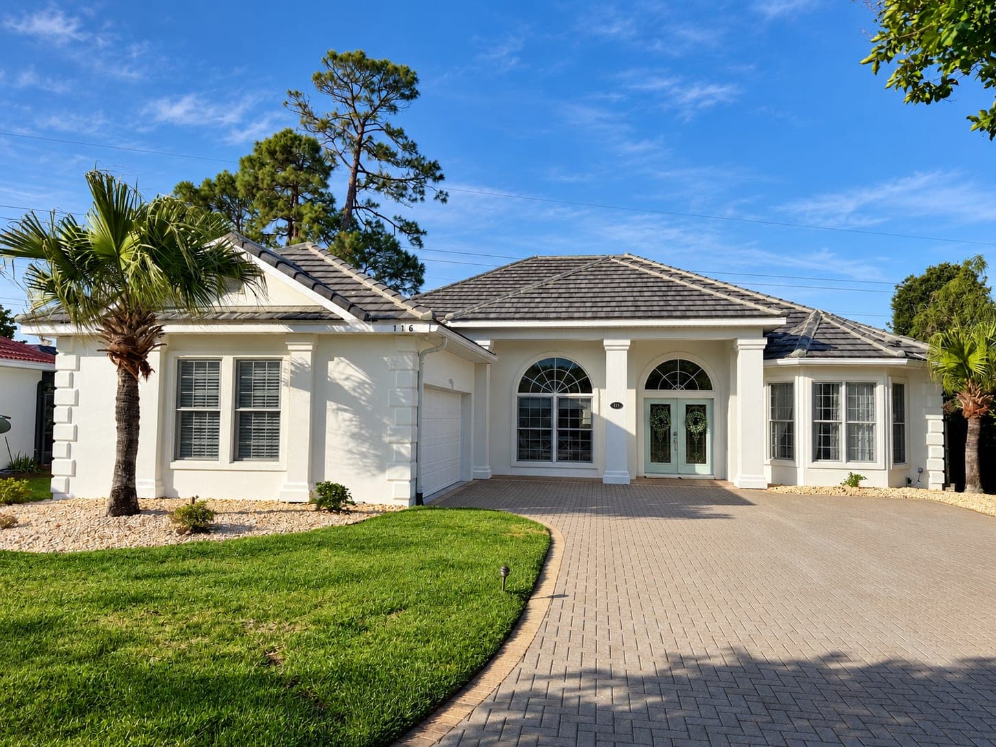 House exterior freshly repainted white, with a paver driveway