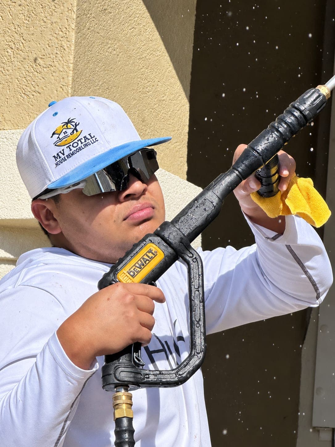 Team member pressure washing the exterior of a house